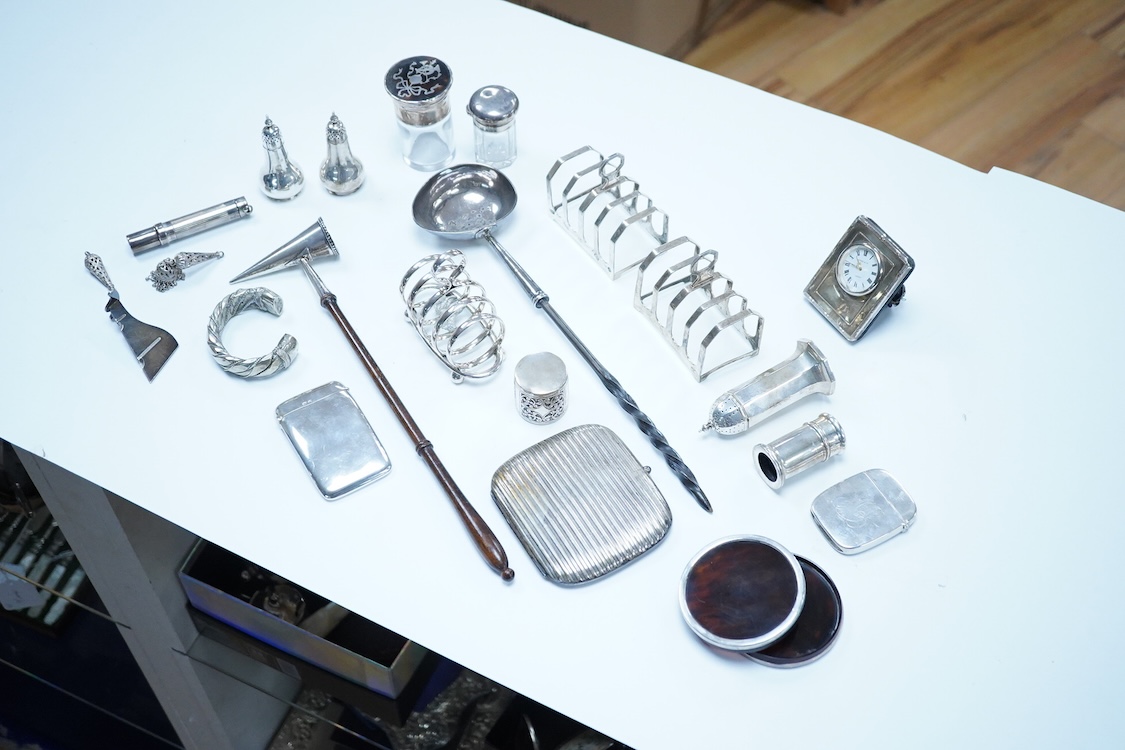 A group of assorted silver, to include a pair of modern five bar toast racks, a George V card case, a sterling vesta case, four assorted condiments, two mounted toilet bottles, mounted timepiece, a modern wooden handled